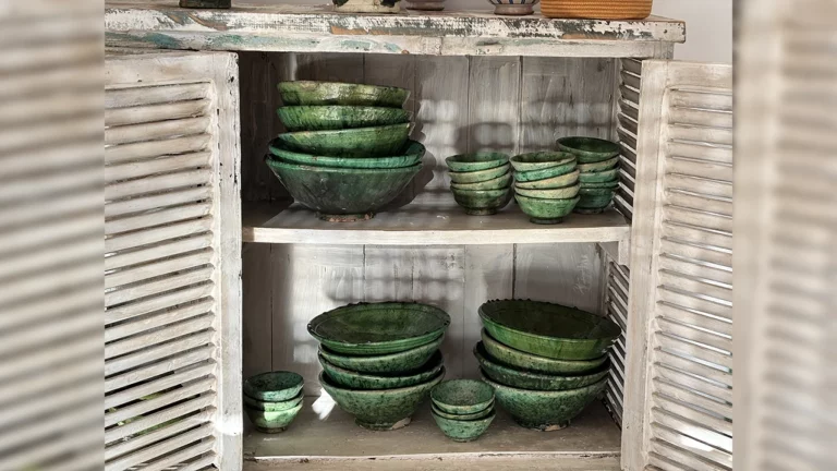 Vaisselle marocaine artisanale en céramique verte de Tamegroute exposée sur une étagère en bois